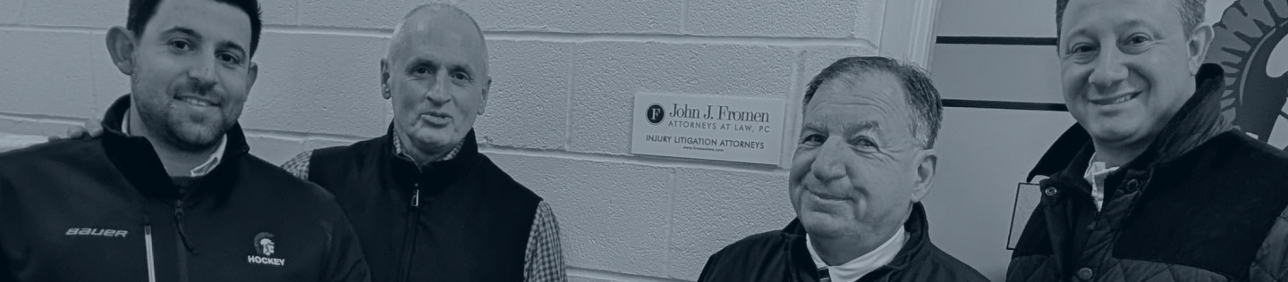 Four men stand in front of a brick wall with a law firm's sign.
